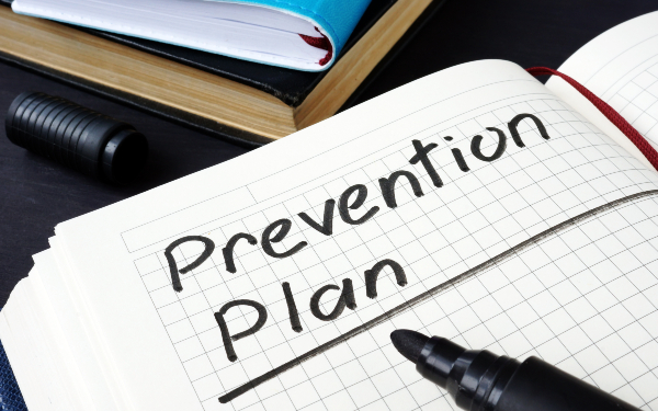 ‘Prevention Plan’ title on lined notebook page with pencil, concept of prevention and organization