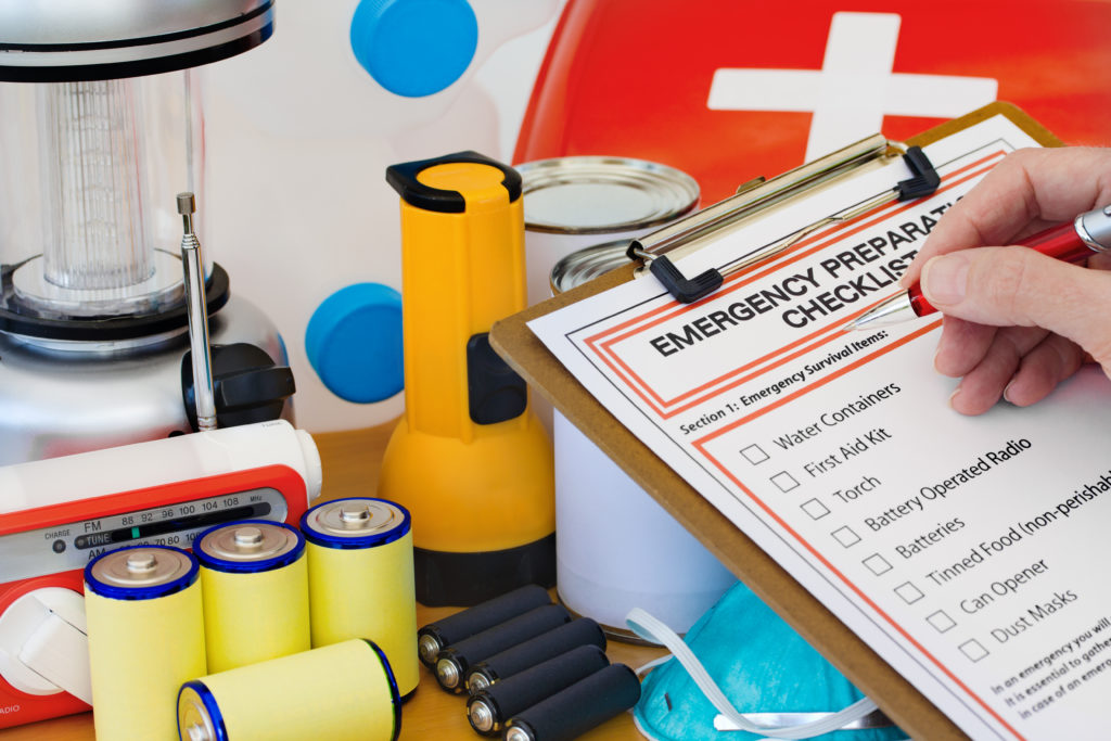 Person checking off emergency preparation checklist infront of its supplies