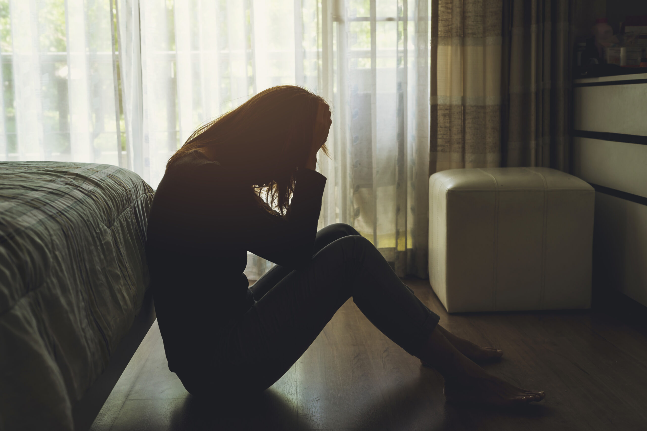 Woman in distress seated on floor in dark room