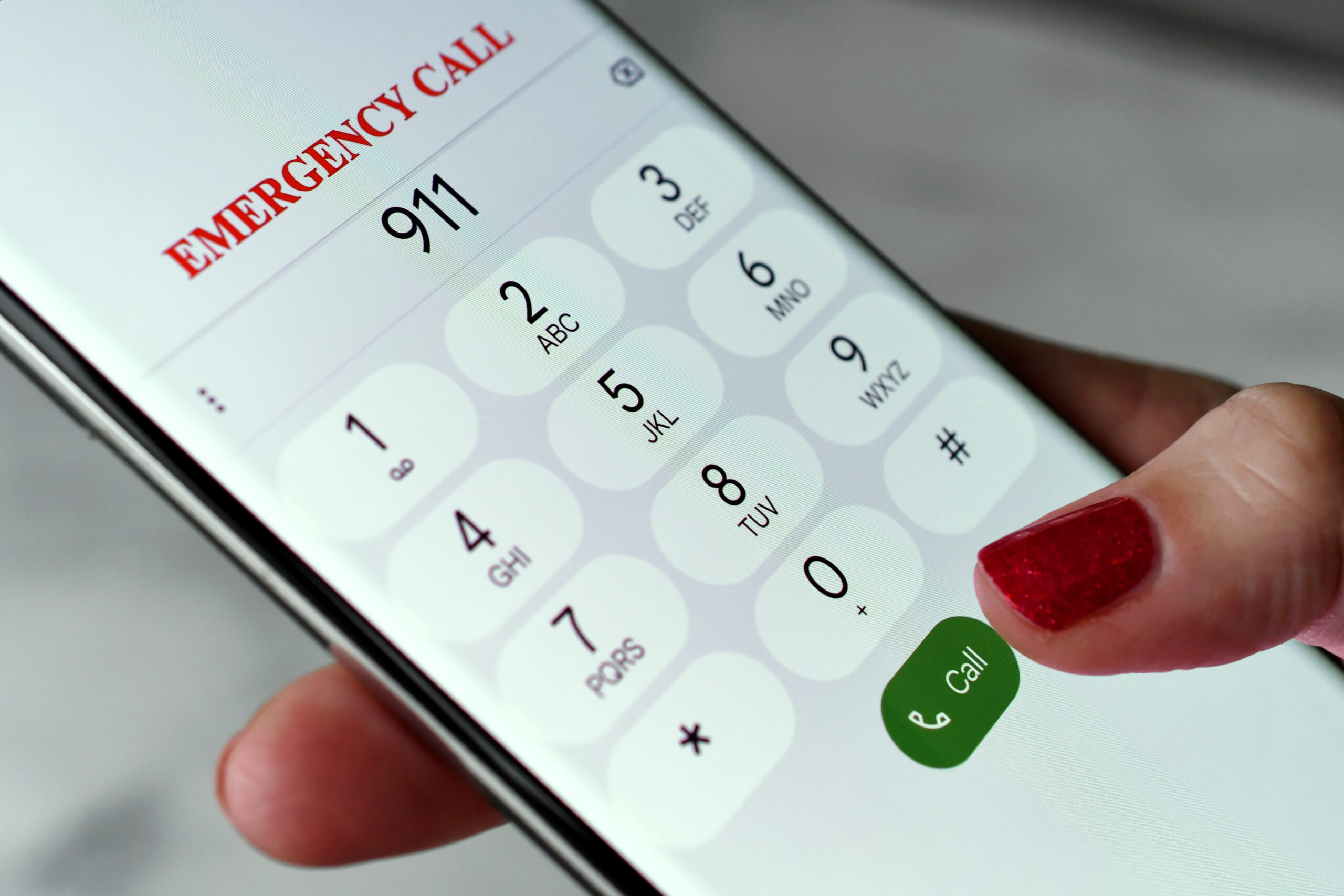 Close-up of a person's finger pressing the Call button on a smartphone after dialing "911" for an emergency call, highlighting public safety and rapid response