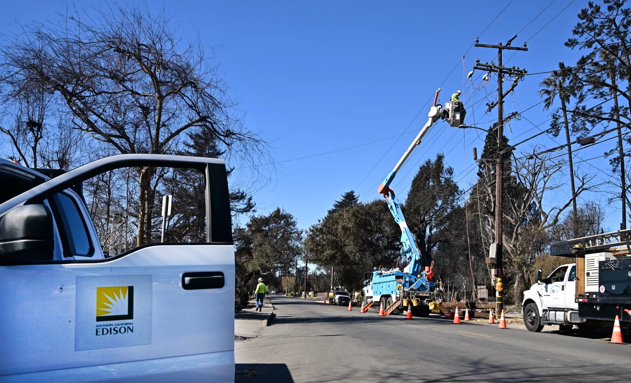 Southern California Edison (SCE) worker repairing power lines from a bucket truck on a sunny day