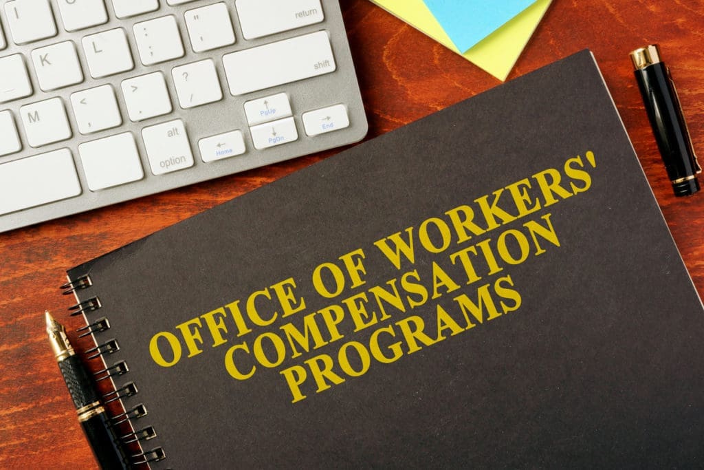 Office of Workers’ Compensation Programs booklet on desk with pen and keyboard