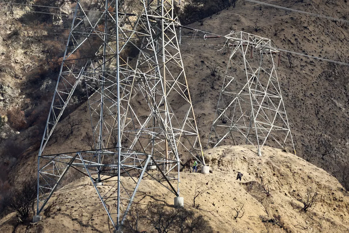 High-voltage power transmission towers on wildfire-scorched hillside, representing electrical infrastructure, utility lines, wildfire damage, and energy grid resilience