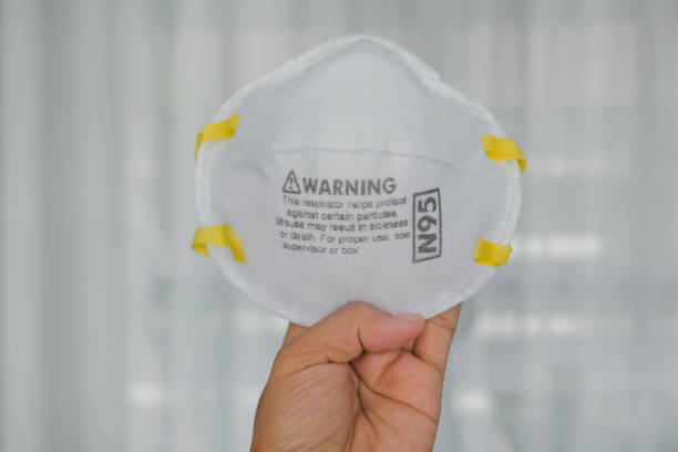 N95 respirator mask held in hand, representing personal protective equipment (PPE), respiratory protection, workplace safety, air quality protection, and health prevention measures.