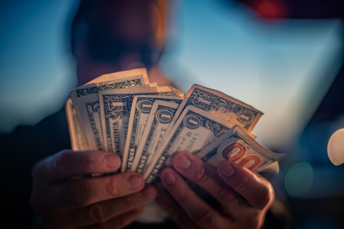 Person holding a stack of cash, representing financial compensation, settlement payouts, insurance claim payments, economic damages, and monetary recovery in personal injury and wrongful death cases.